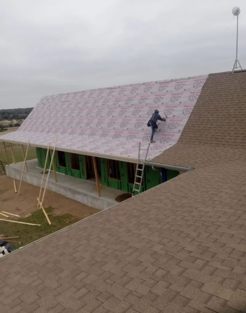 Worker preparing underlayment for a metal roof installation in Audubon
